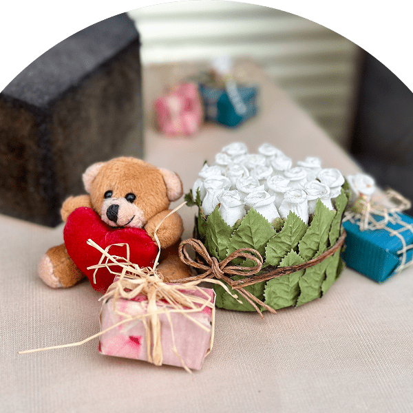 Teddy bear with gifts and white roses.